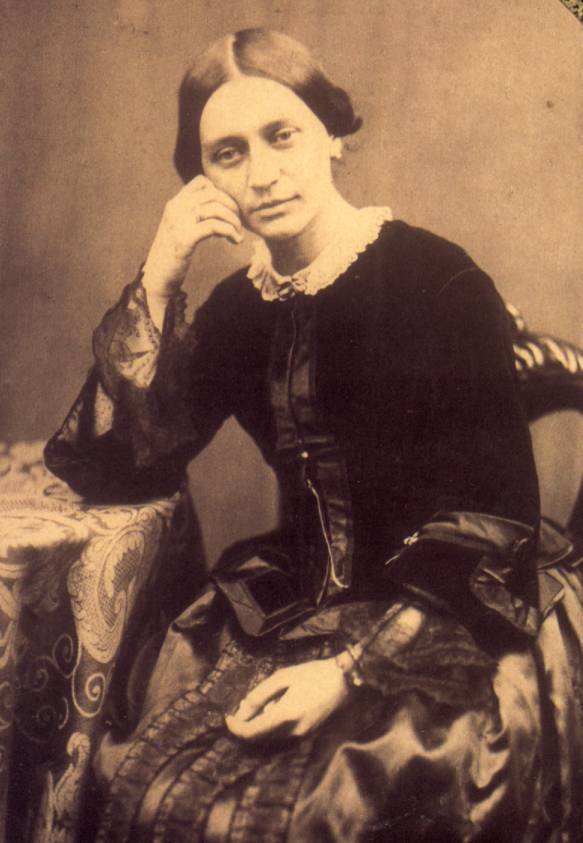 Sepia photograph of woman in Victorian clothing leaning on arm on lacey table.