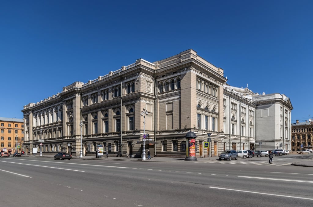 Classical beige building with wide street in front.