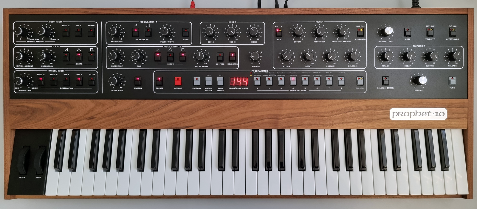 Keyboard on wood panel with lots of knobs and switches.